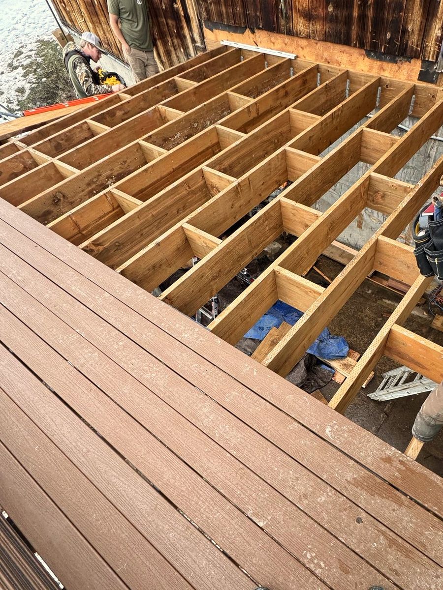 Deck framing seen from above: joists and blocking laid out in a grid, with finished boards running across the foreground.